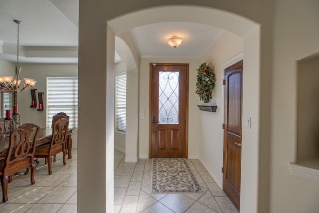 entrance foyer featuring light tile patterned floors, an inviting chandelier, plenty of natural light, and ornamental molding