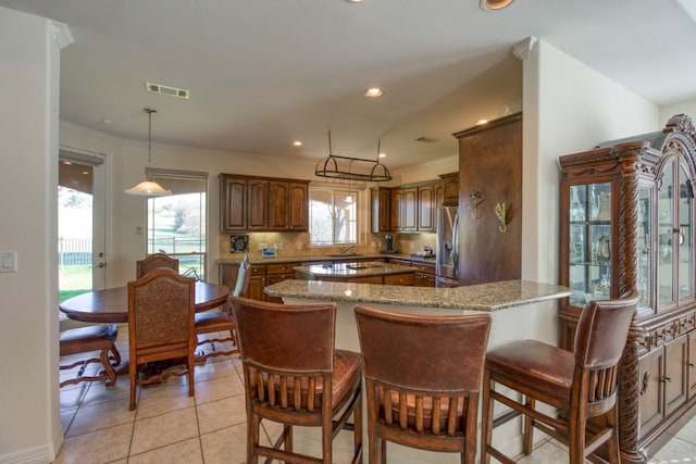 kitchen featuring decorative light fixtures, stainless steel fridge, light tile patterned floors, tasteful backsplash, and stone countertops