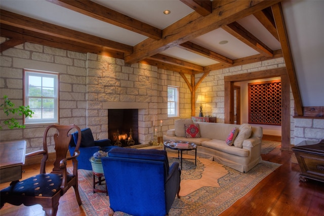 living room featuring beam ceiling, dark hardwood / wood-style floors, and a stone fireplace