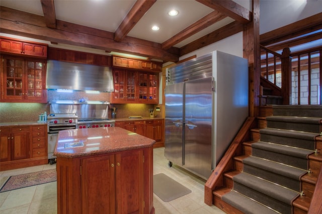 kitchen featuring beamed ceiling, a center island, tasteful backsplash, stainless steel appliances, and extractor fan