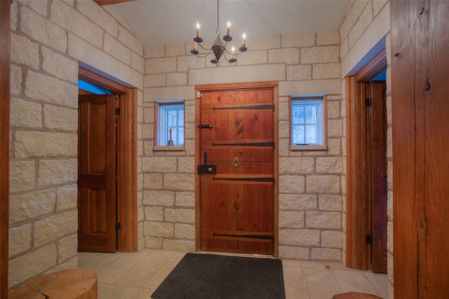 entryway featuring an inviting chandelier, light tile patterned floors, and plenty of natural light