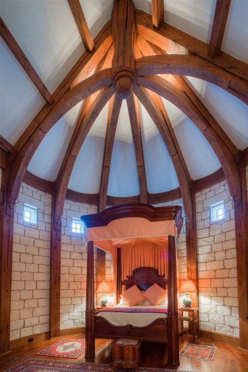 bedroom featuring brick wall and vaulted ceiling with beams