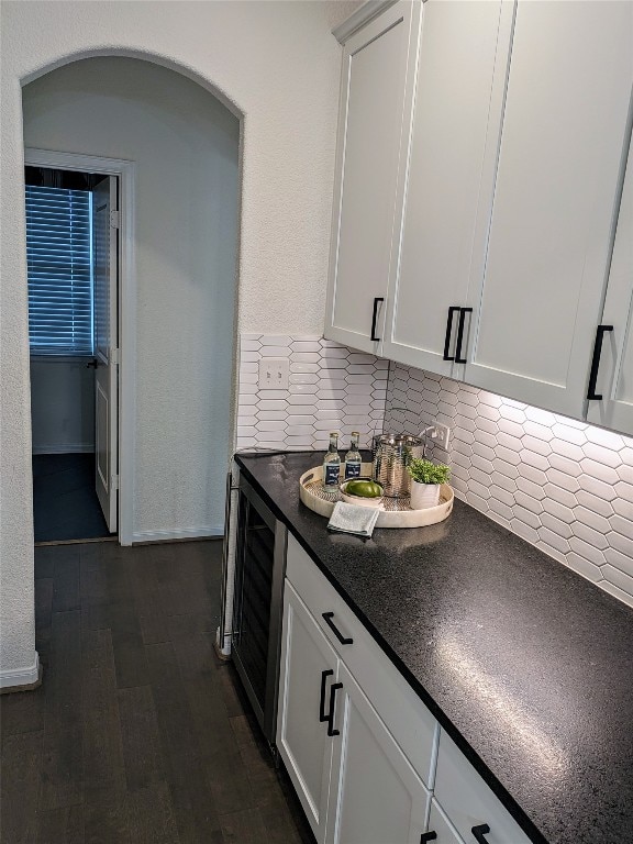 kitchen with backsplash, dark hardwood / wood-style floors, white cabinetry, and beverage cooler