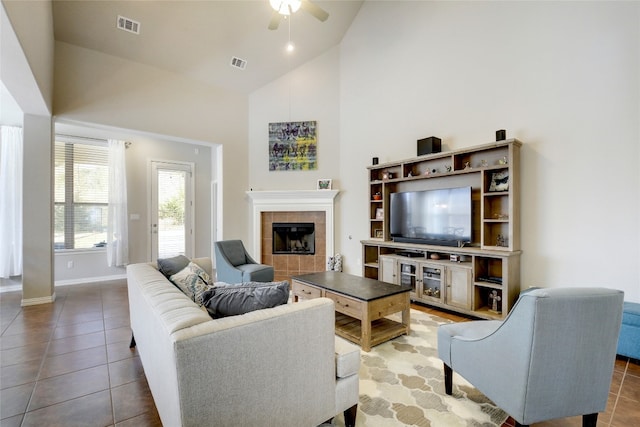 living room with a tile fireplace, ceiling fan, high vaulted ceiling, and tile patterned flooring