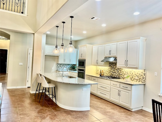 kitchen featuring stainless steel appliances, light stone countertops, a kitchen bar, and white cabinets