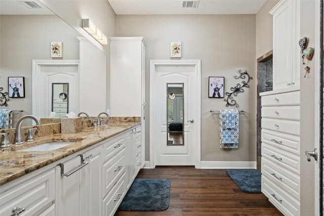 bathroom featuring vanity with extensive cabinet space, dual sinks, and hardwood / wood-style floors