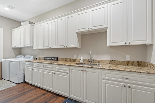 kitchen featuring sink, light stone counters, dark wood-type flooring, white cabinetry, and washing machine and dryer