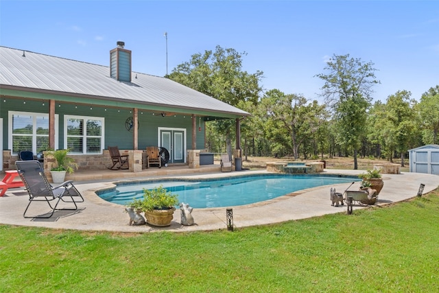 view of swimming pool with a yard, a patio area, an in ground hot tub, and a storage unit