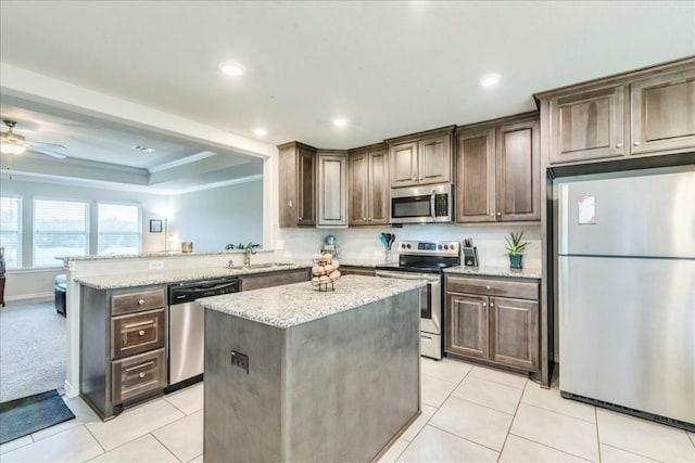 kitchen featuring stainless steel appliances, a kitchen island, dark brown cabinets, and kitchen peninsula