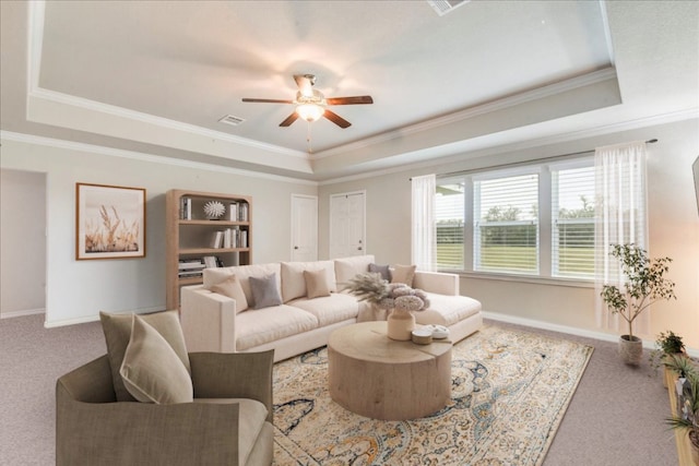 living room featuring crown molding, a tray ceiling, ceiling fan, and carpet flooring