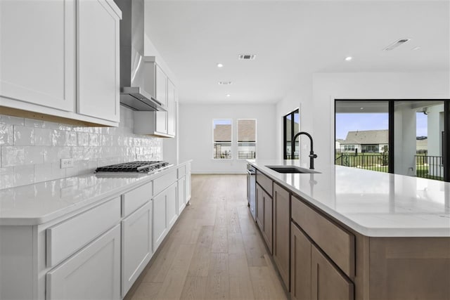 kitchen featuring white cabinets, sink, and wall chimney range hood