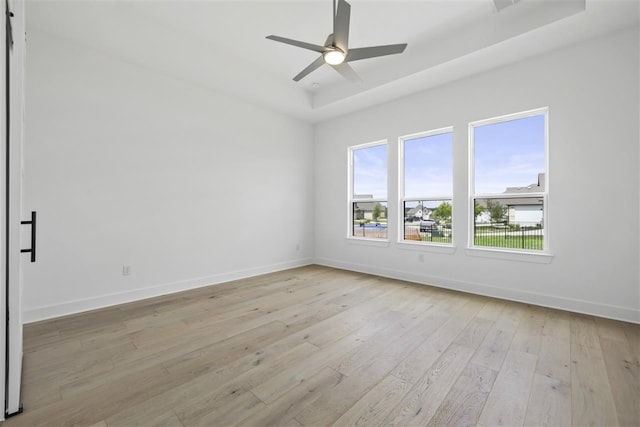 unfurnished room with light hardwood / wood-style floors, ceiling fan, and a raised ceiling