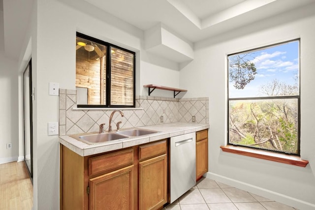 kitchen with sink, backsplash, dishwasher, and light tile patterned flooring