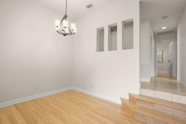 unfurnished room featuring a chandelier and light hardwood / wood-style flooring