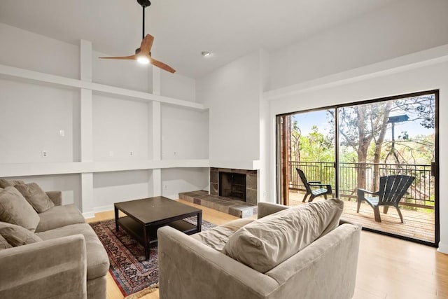 living room with light hardwood / wood-style flooring, a tile fireplace, and ceiling fan