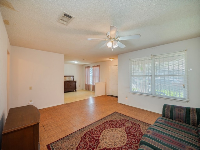 living room featuring a textured ceiling, ceiling fan, and light parquet floors