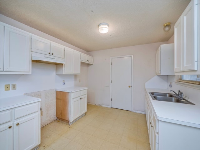 kitchen featuring white cabinetry, a textured ceiling, sink, and light tile floors