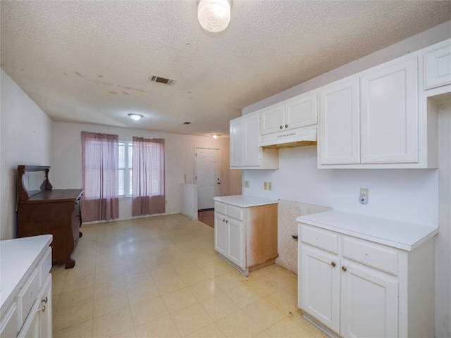 kitchen featuring white cabinetry, a textured ceiling, and light tile floors