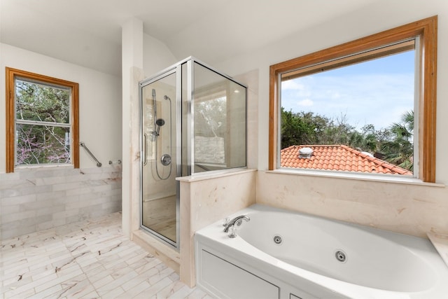 bathroom featuring a healthy amount of sunlight, plus walk in shower, and tile walls