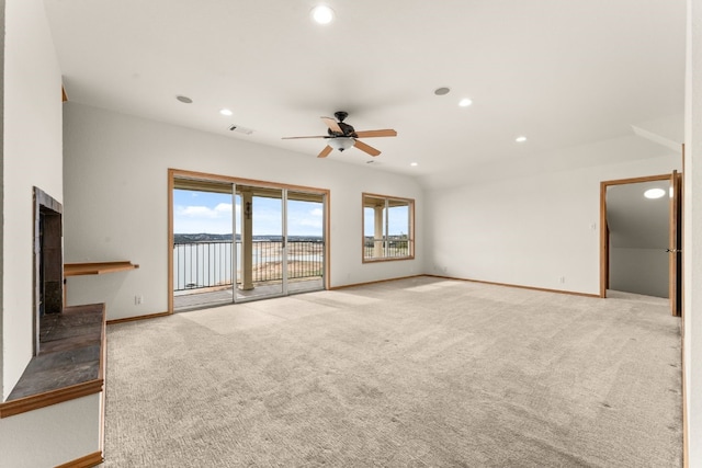 unfurnished living room featuring light carpet, ceiling fan, and a water view