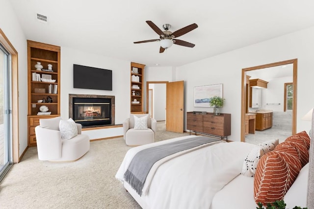 bedroom featuring ensuite bathroom, light colored carpet, and ceiling fan