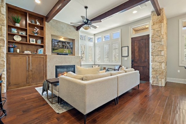 living room with a fireplace, dark hardwood / wood-style flooring, ceiling fan, and beamed ceiling