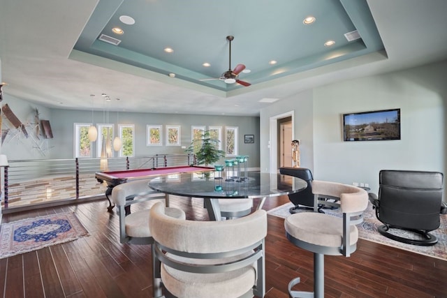 game room featuring a tray ceiling, ceiling fan, and dark wood-type flooring