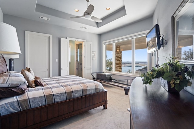 bedroom with carpet floors, a raised ceiling, and ceiling fan