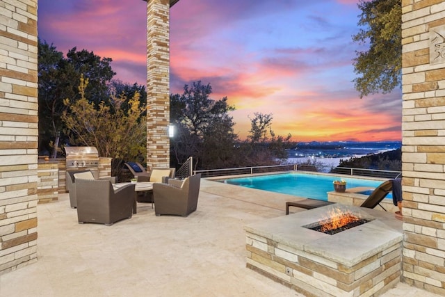 pool at dusk with a fire pit and a patio