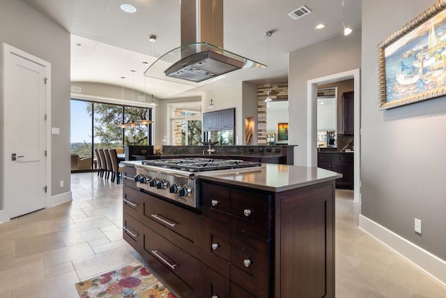 kitchen with lofted ceiling, decorative backsplash, a kitchen island, island exhaust hood, and stainless steel gas cooktop