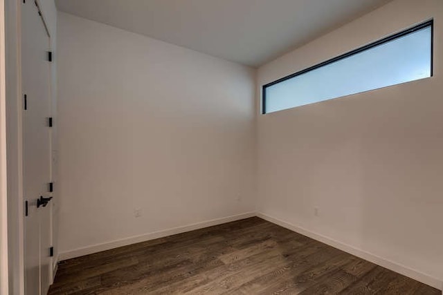 unfurnished room featuring dark hardwood / wood-style floors and a barn door