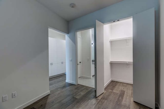 unfurnished bedroom with a walk in closet, dark hardwood / wood-style flooring, and a closet