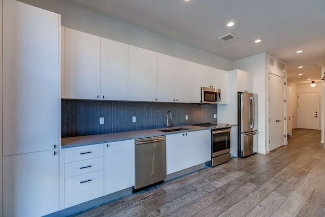 kitchen with white cabinetry, sink, stainless steel appliances, and light hardwood / wood-style floors