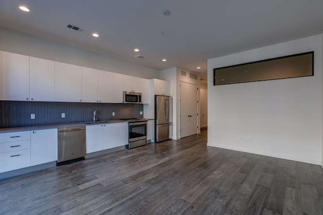 kitchen featuring sink, dark wood-type flooring, white cabinetry, stainless steel appliances, and decorative backsplash