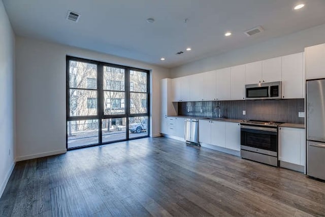 kitchen featuring sink, dark hardwood / wood-style flooring, stainless steel appliances, decorative backsplash, and white cabinets