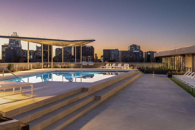 pool at dusk with a patio area