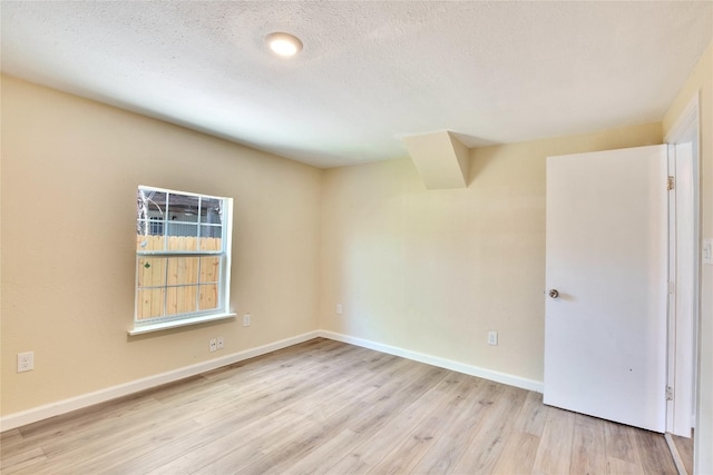 unfurnished room with a textured ceiling and light hardwood / wood-style flooring