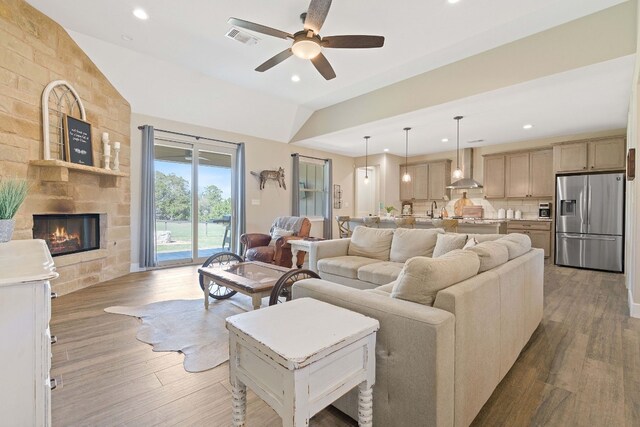 living room featuring a fireplace, wood-type flooring, sink, and ceiling fan