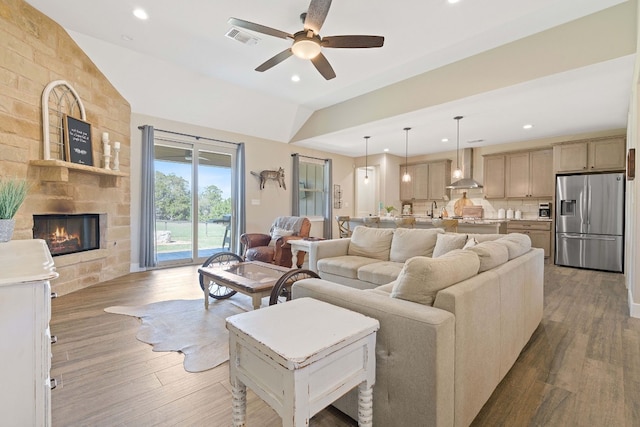 living room featuring hardwood / wood-style flooring, ceiling fan, lofted ceiling, and a fireplace