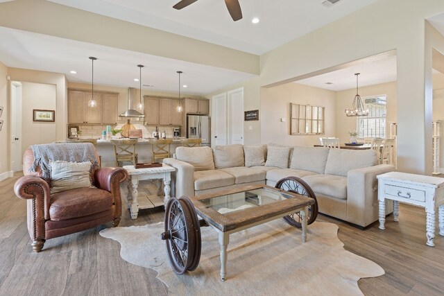 living room with ceiling fan with notable chandelier and wood-type flooring