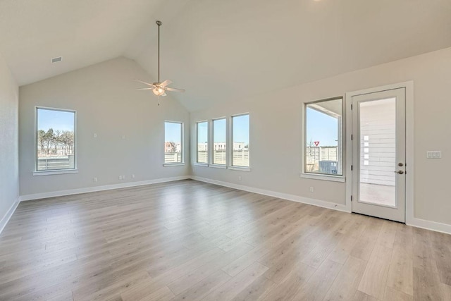 unfurnished living room featuring plenty of natural light, lofted ceiling, a ceiling fan, light wood-style floors, and baseboards