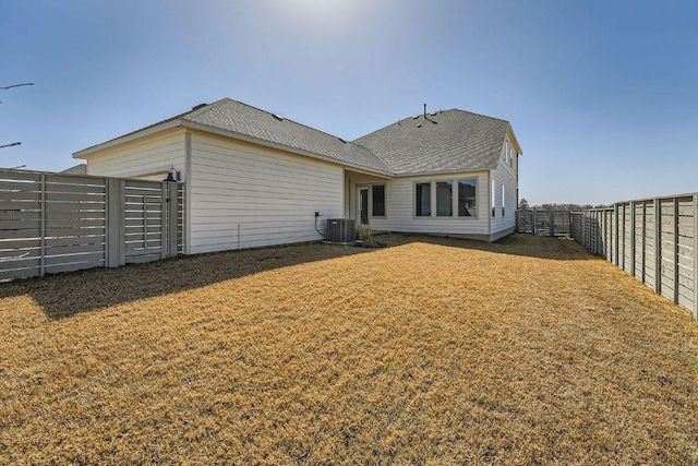 back of property with central AC unit and a shingled roof