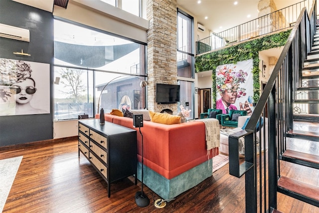 living room with a stone fireplace, dark wood-type flooring, a wealth of natural light, and a towering ceiling