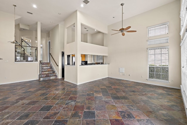 unfurnished living room featuring ceiling fan and a towering ceiling