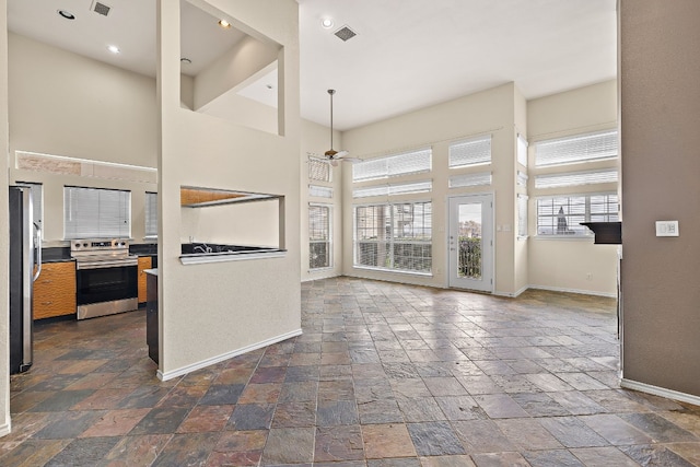 kitchen with ceiling fan, a high ceiling, and appliances with stainless steel finishes