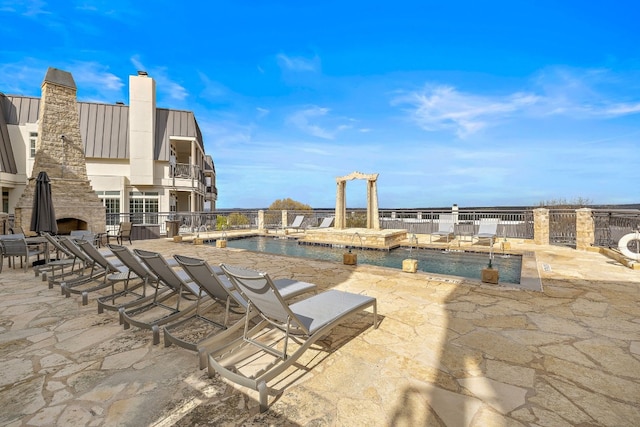 view of patio featuring an outdoor stone fireplace and a community pool