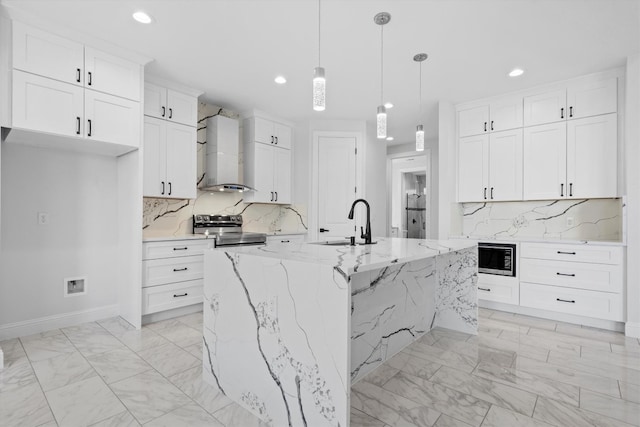 kitchen featuring a kitchen island with sink, appliances with stainless steel finishes, sink, light stone counters, and wall chimney exhaust hood