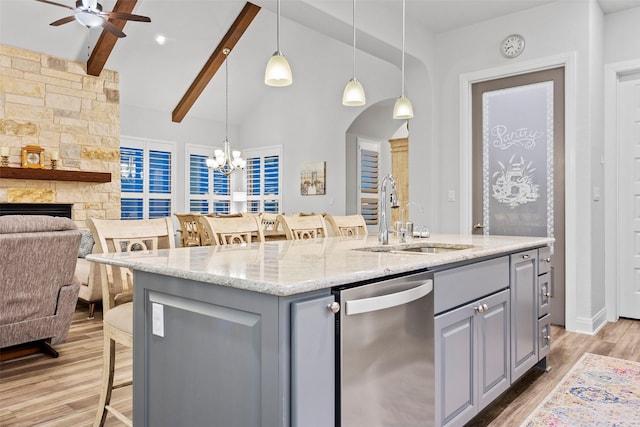 kitchen with sink, light stone counters, stainless steel dishwasher, and gray cabinets