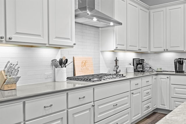 kitchen featuring white cabinets, stainless steel gas stovetop, wall chimney range hood, and tasteful backsplash