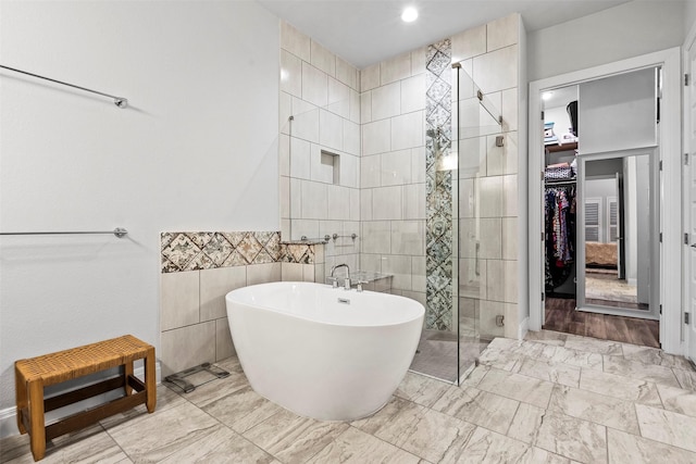 bathroom featuring shower with separate bathtub and tile walls